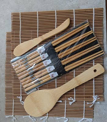 reviewer photo of the sushi kit, which includes two rolling mats, chopsticks, a rice spreader, and paddle