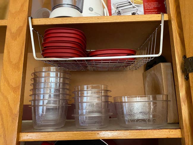 An under-the-shelf basket holding lids in a cabinet