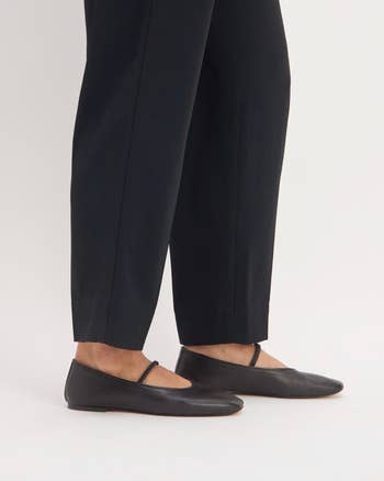 Person wearing achromatic  ballet flats with strap detail