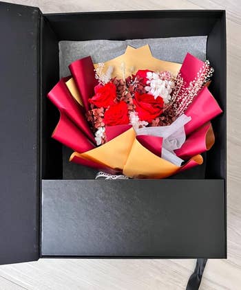A boxed bouquet with red roses and assorted flowers,