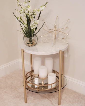 reviewer photo of the marble and gold end table holding flowers and candles