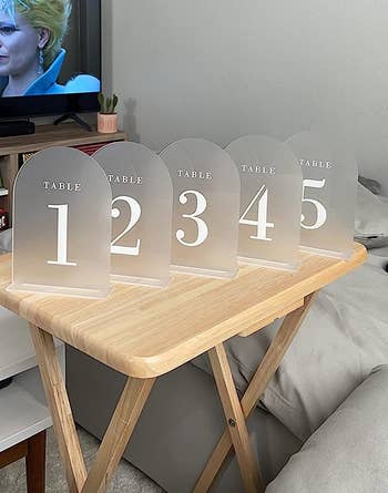 a reviewer photo of five frosted arch-shaped table marker signs 