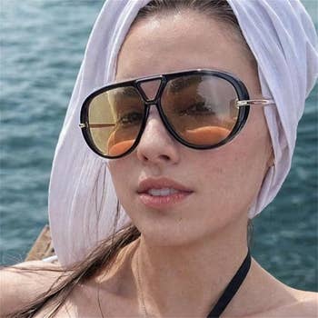 model wearing ample sunglasses and a achromatic headscarf, posed by water, successful a relaxed, stylish look