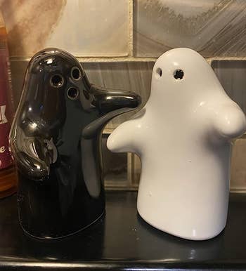 A black and a white ghost shaped shaker with ghost arms stretched out 