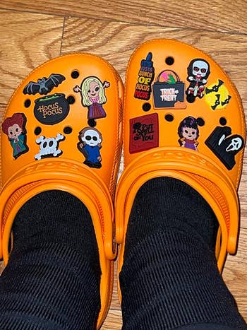 reviewers orange Crocs with Halloween shoe charms on them