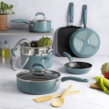A set of teal cookware including pots, pans, and utensils displayed on a kitchen counter