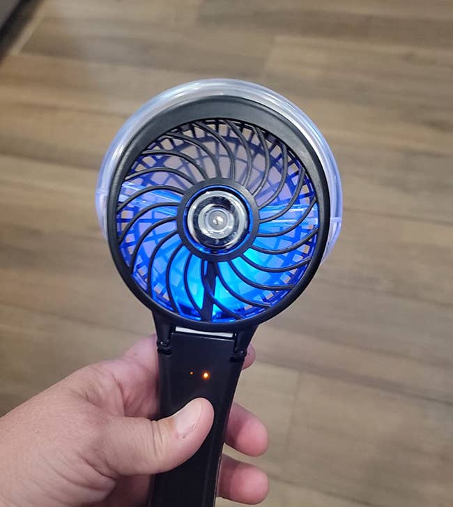 a reviewer holding their black portable fan