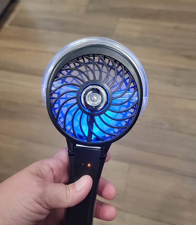 a reviewer holding their black portable fan