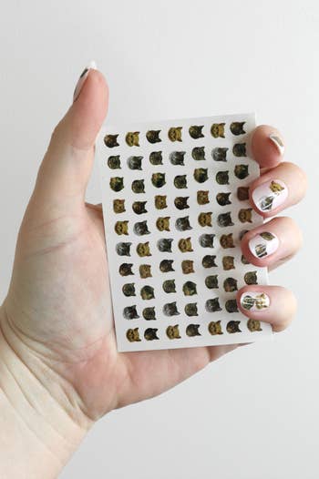 hand holding a sheet of cat nail decals