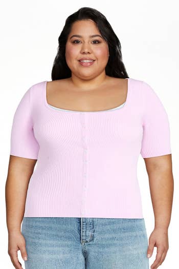 Person wearing a ribbed button-up top and jeans, smiling at the camera