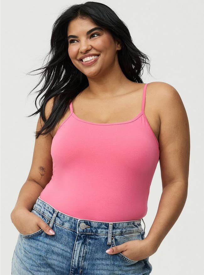 Person smiling, wearing a pinkish sleeveless apical and bluish jeans. Featured successful a buying article