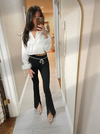Person taking a mirror selfie wearing a white blouse with feather cuffs