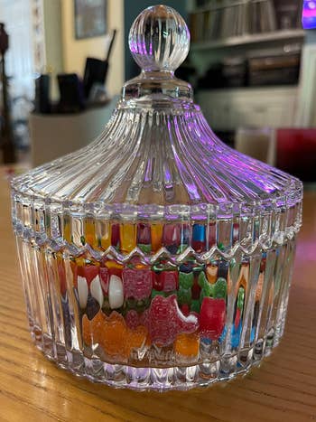 same reviewer's side view photo of the glass candy dish filled with candy, with the cover on