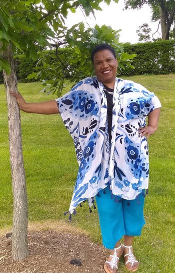 a reviewer wearing the shawl in white with a blue abstract print 