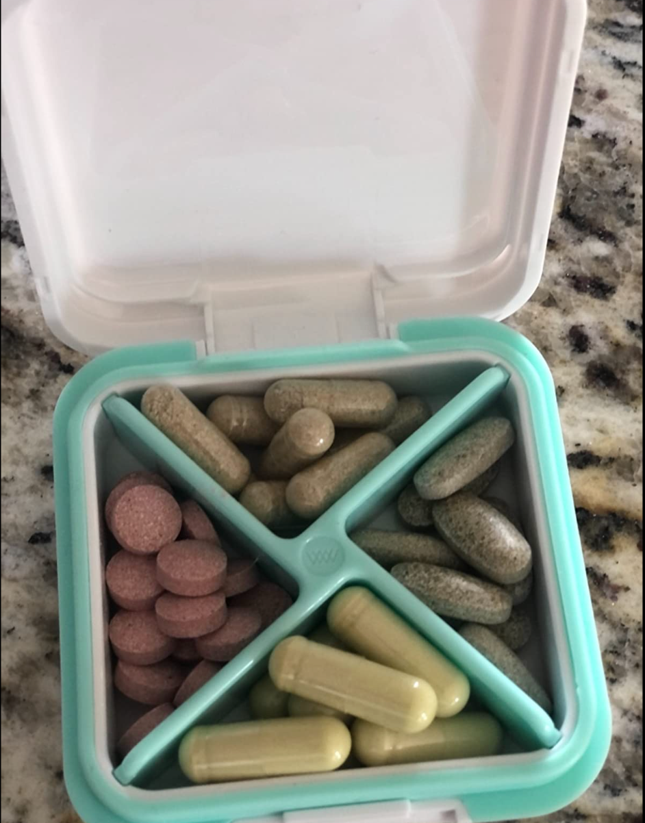 A small pill box with four dividers in it holding vitamins and pills 