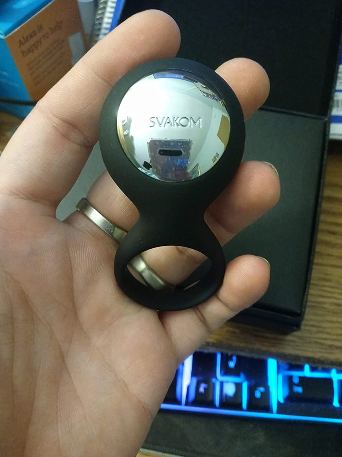 Reviewer holding black cock ring with silvertone accent