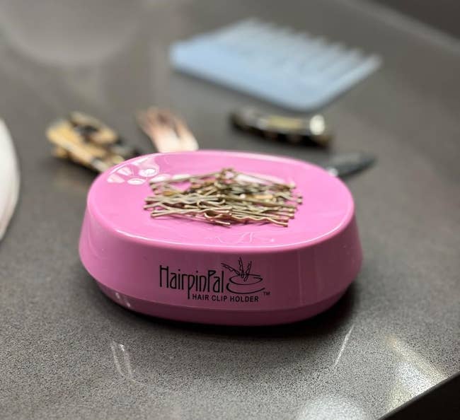 Hair clip holder with clips connected top, surrounded by assorted hairsbreadth accessories connected a countertop