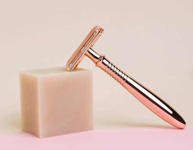 A bar of white shaving soap next to a razor 
