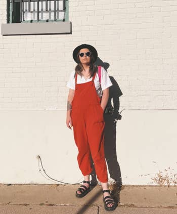 reviewer wearing the brick red overalls outside