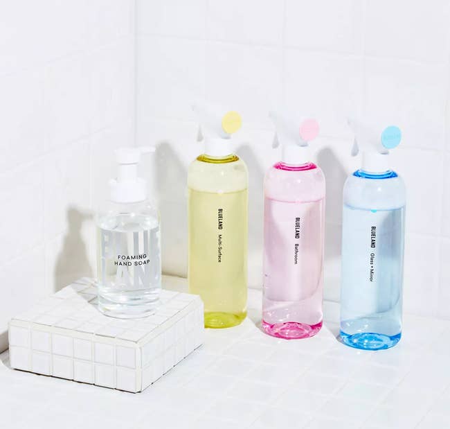 The spray cleaning bottles in yellow, pink, blue, and clear tones 