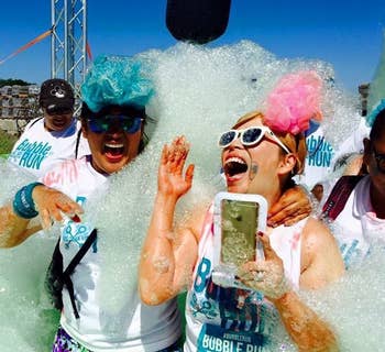 reviewer holding the phone pouch while covered in bubbles during a bubble run
