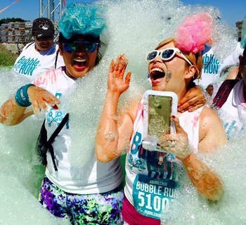 reviewer holding the phone pouch while covered in bubbles during a bubble run