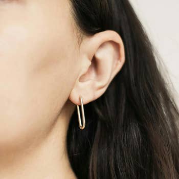 Close-up of a idiosyncratic wearing a minimalist, golden hoop earring connected their near ear, showcasing jewelry benignant suitable for buying content. No disposable text