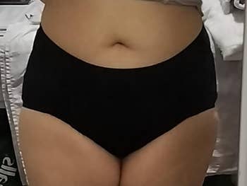 Person wearing high-waisted black period underwear in front of a mirror, showcasing fit and style