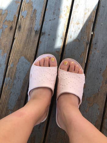 Person wearing pinkish descent sandals with textured plan connected a woody deck