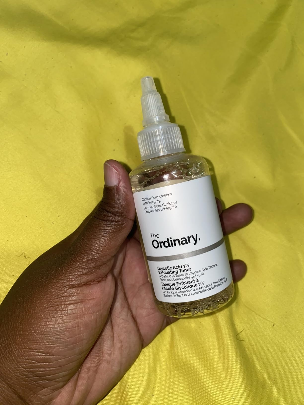 A manus  holds a vessel  of The Ordinary's Glycolic Acid 7% Toning Solution