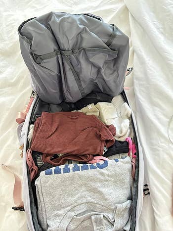 reviewer's open backpack on a bed, with neatly packed clothes and a full compartment on top