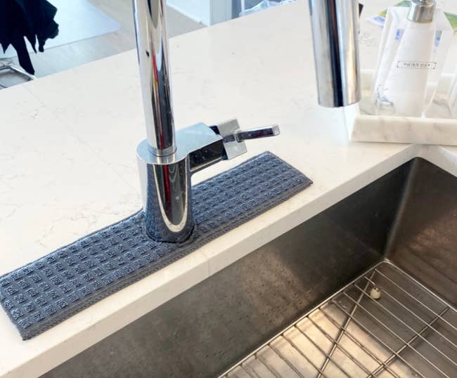 a navy faucet splash catcher around a kitchen faucet