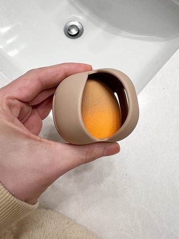 image of reviewer holding sponge container with a makeup sponge inside of it