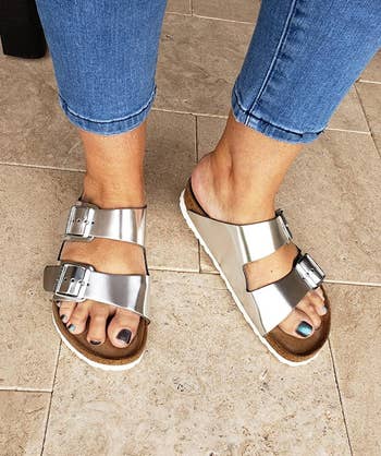 reviewer's feet wearing the silver sandals