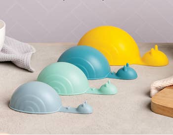 four snail shaped cups in gray, blue, and yellow on a counter 