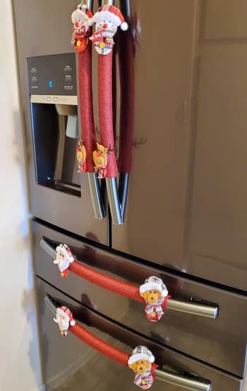 reviewer photo of the snowpal, rudolph, santa, and teddy bear handle covers on the handles of a refrigerator