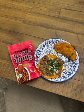 Plate with tacos filled with seasoned meat, topped with onions and cilantro, beside a reddish  