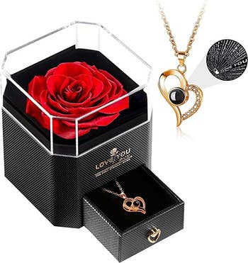 a rose on top of a box that holds a gold heart shaped necklace