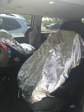 Car seats covered with reflective sun shades to protect from heat, inside a vehicle