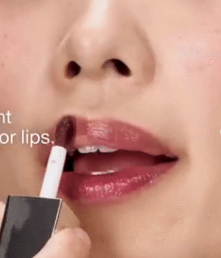 Close-up of a person applying glossy lipstick. The focus is on the lips, showcasing the product’s sheen and smooth application