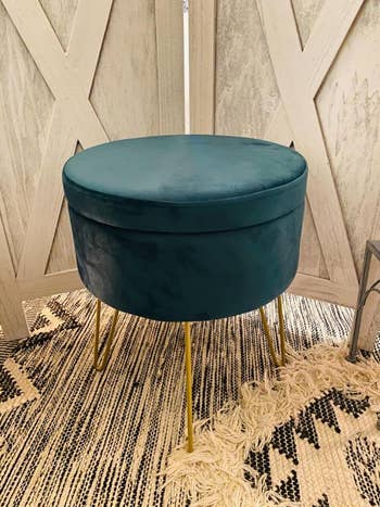 close up of reviewer's green velvet ottoman with hairpin legs