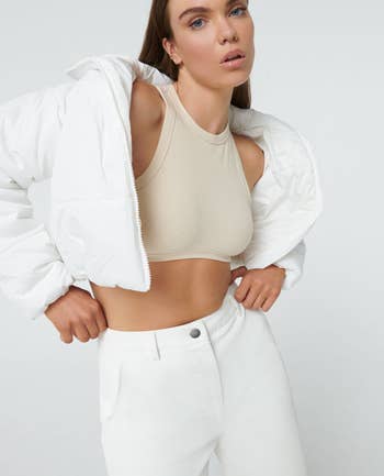a model wearing the same jacket in white over a crop top 