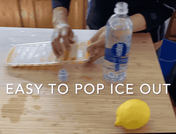 a gif of a model popping ice cubes out of the tray and putting them inside of a plastic water bottle 