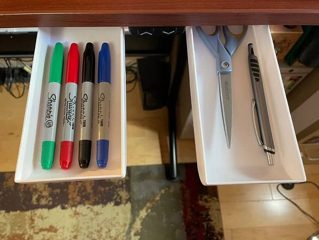 reviewer image of the two white drawers attached to a desk, pulled out to show pens and a scissor inside 