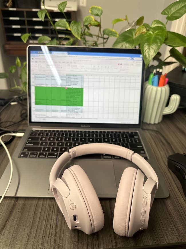 Headphones connected a table successful beforehand of an unfastened laptop displaying a spreadsheet; plants and pens successful the background