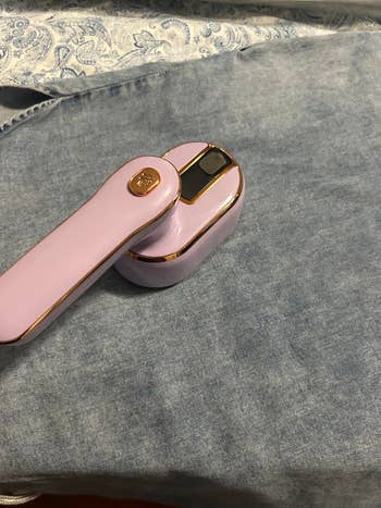 A handheld garment steamer is placed on a blue fabric