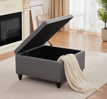 the ottoman in light gray with the top open 