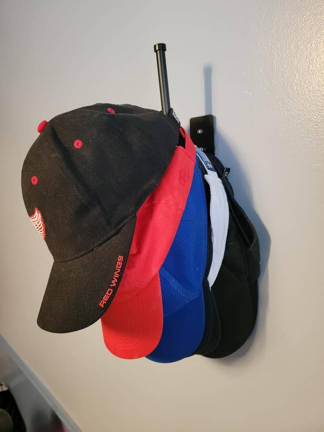 A variety of baseball caps hanging on a wall-mounted rack, suitable for shopping interests