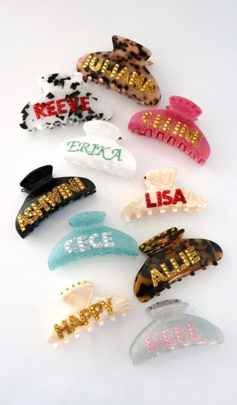 an assortment of claw hair clips in different colors and styles, and with different names and words on them
