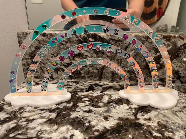 a reviewer photo of the rainbow earring holder with several studs on it
